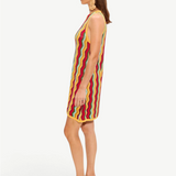 The Hazel Knit Dress is a sleeveless crochet mini dress featuring a colorful vertical zigzag pattern, worn with tan wedge sandals.