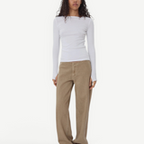 Model wearing KABE SHOP INC Sport Jean in tan denim with a relaxed fit and white long-sleeve top on a grey background