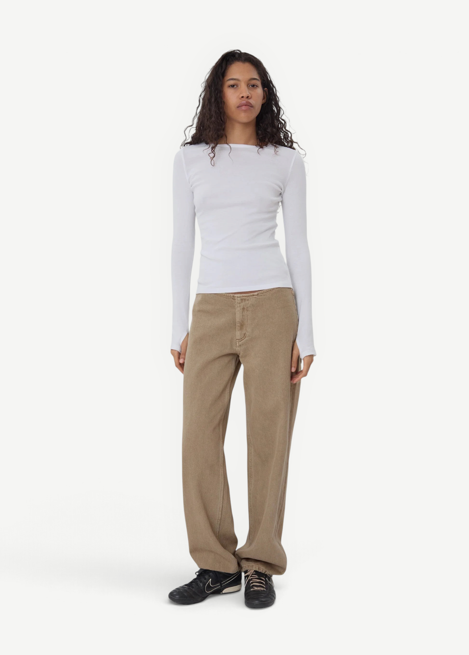 Model wearing KABE SHOP INC Sport Jean in tan denim with a relaxed fit and white long-sleeve top on a grey background