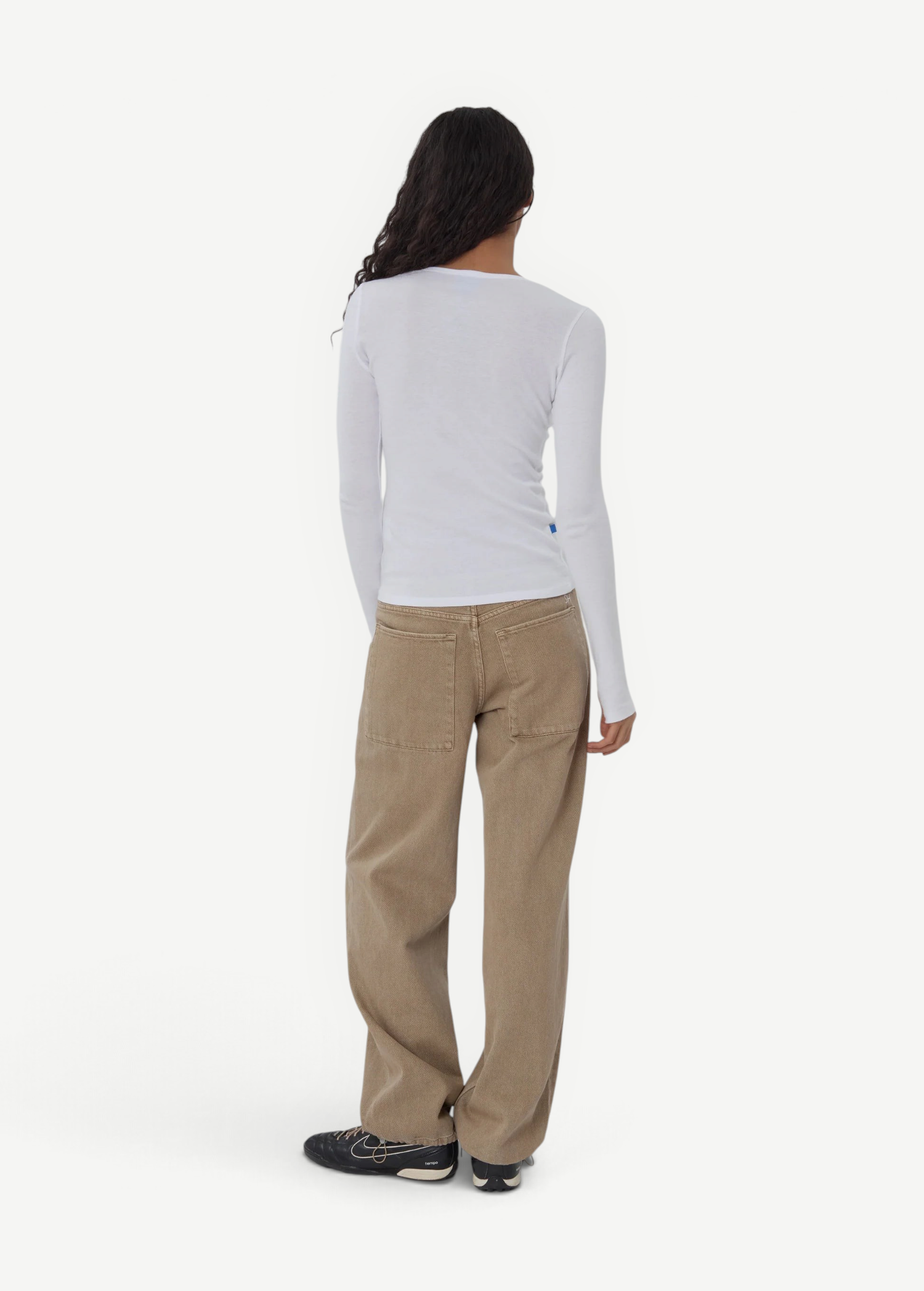 Model wearing KABE SHOP INC Sport Jean in tan denim with a relaxed fit, paired with a white long-sleeve top.
