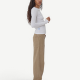 Model wearing KABE SHOP INC Sport Jean in tan denim with a relaxed fit, paired with a white long-sleeve top.