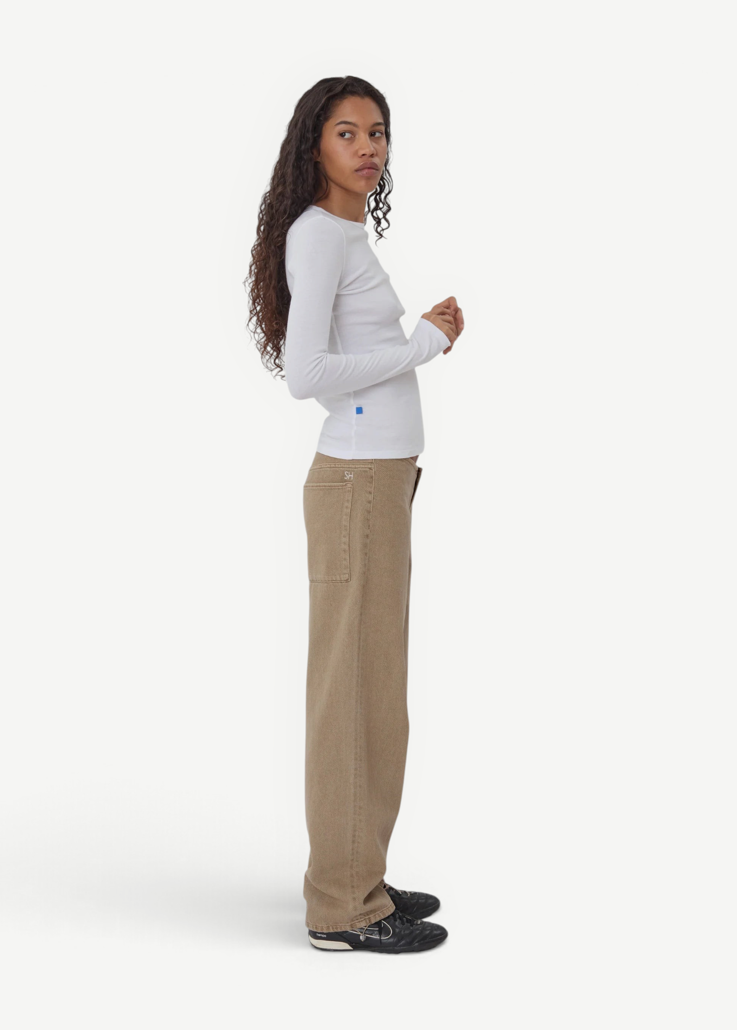 Model wearing KABE SHOP INC Sport Jean in tan denim with a relaxed fit, paired with a white long-sleeve top.