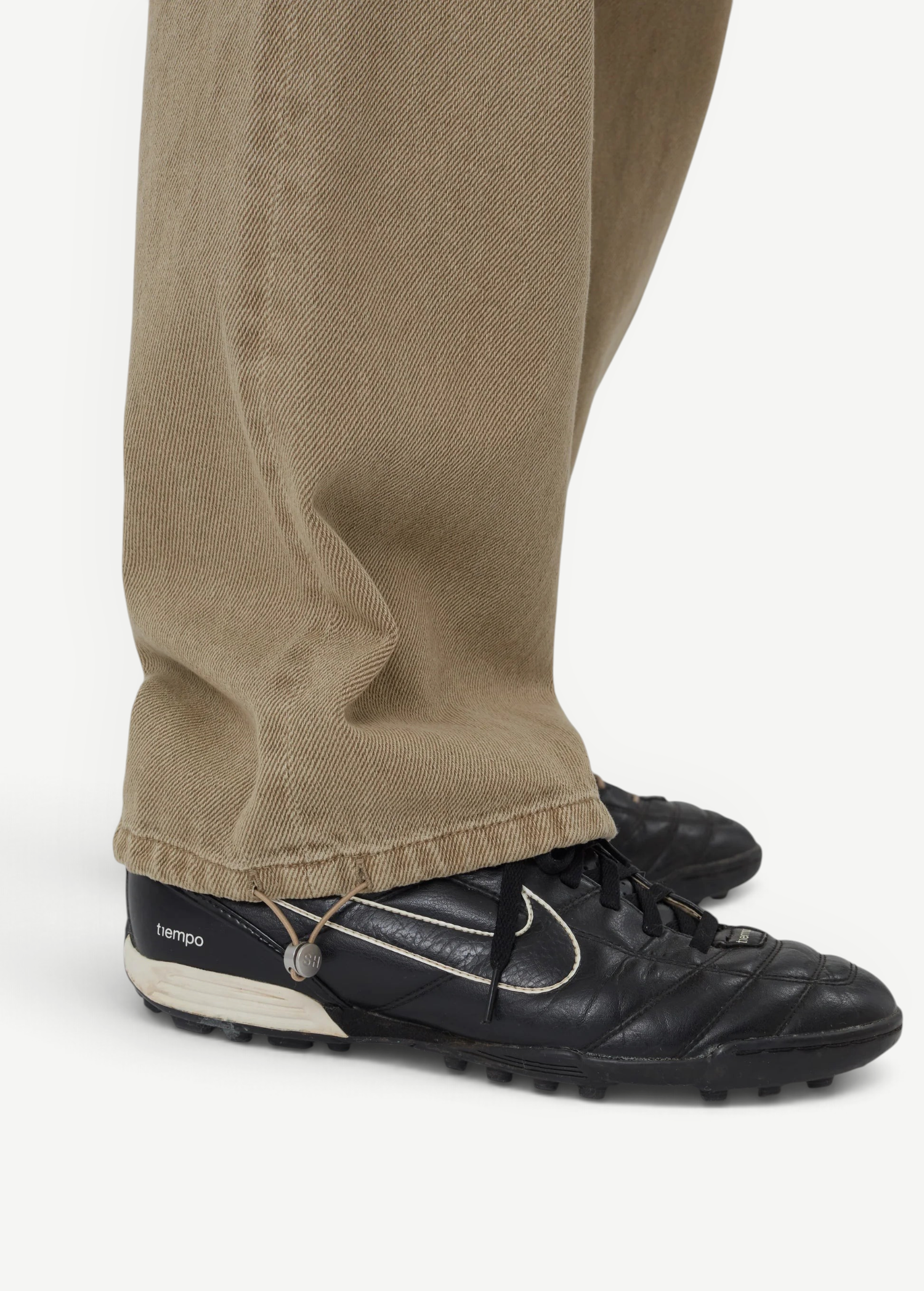 KABE SHOP INC Sport Jean in tan denim with a relaxed fit and adjustable drawstring hem, worn with black sneakers.