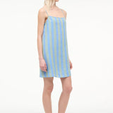 A person wearing a blue and light green striped Laura Mini Dress with spaghetti straps and brown flip-flops, perfect for warm-weather dressing.