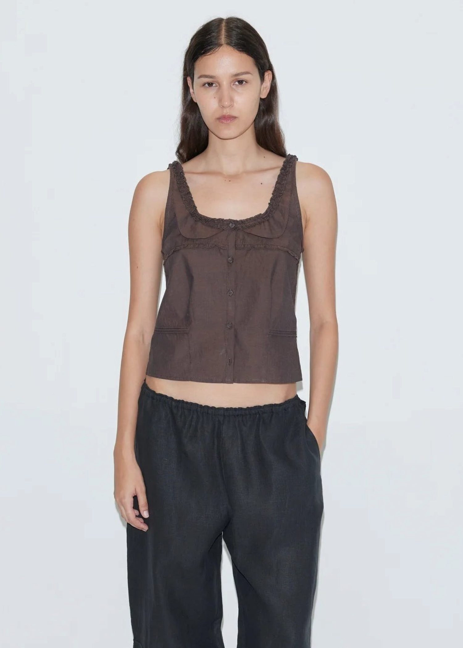 Model wearing KABE SHOP INC Deiji Studios brown cotton poplin tank top with frill detailing and button-through front.