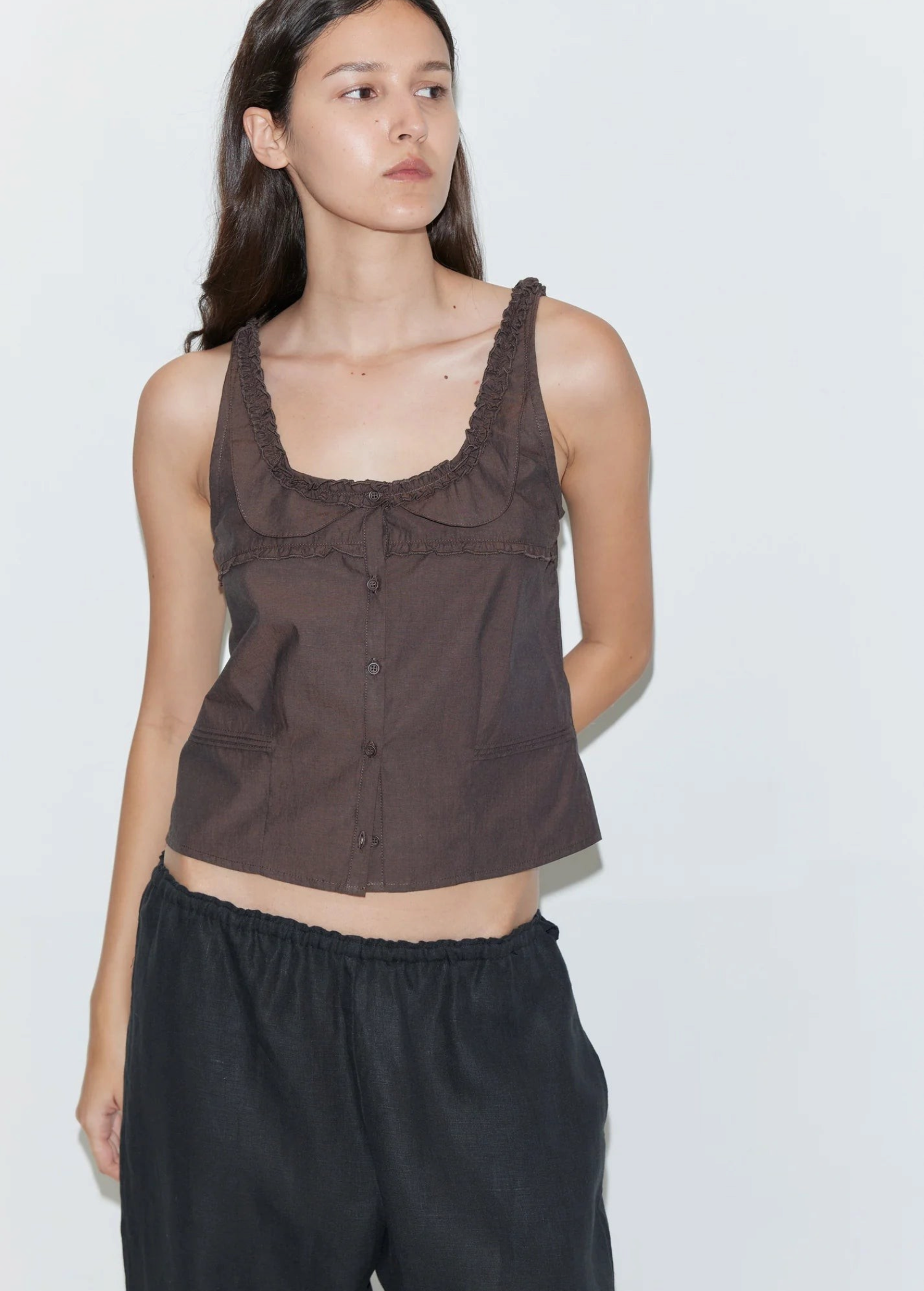 Model wearing a brown KABE SHOP INC Deiji Studios cotton poplin tank top with frill details and button-through front.