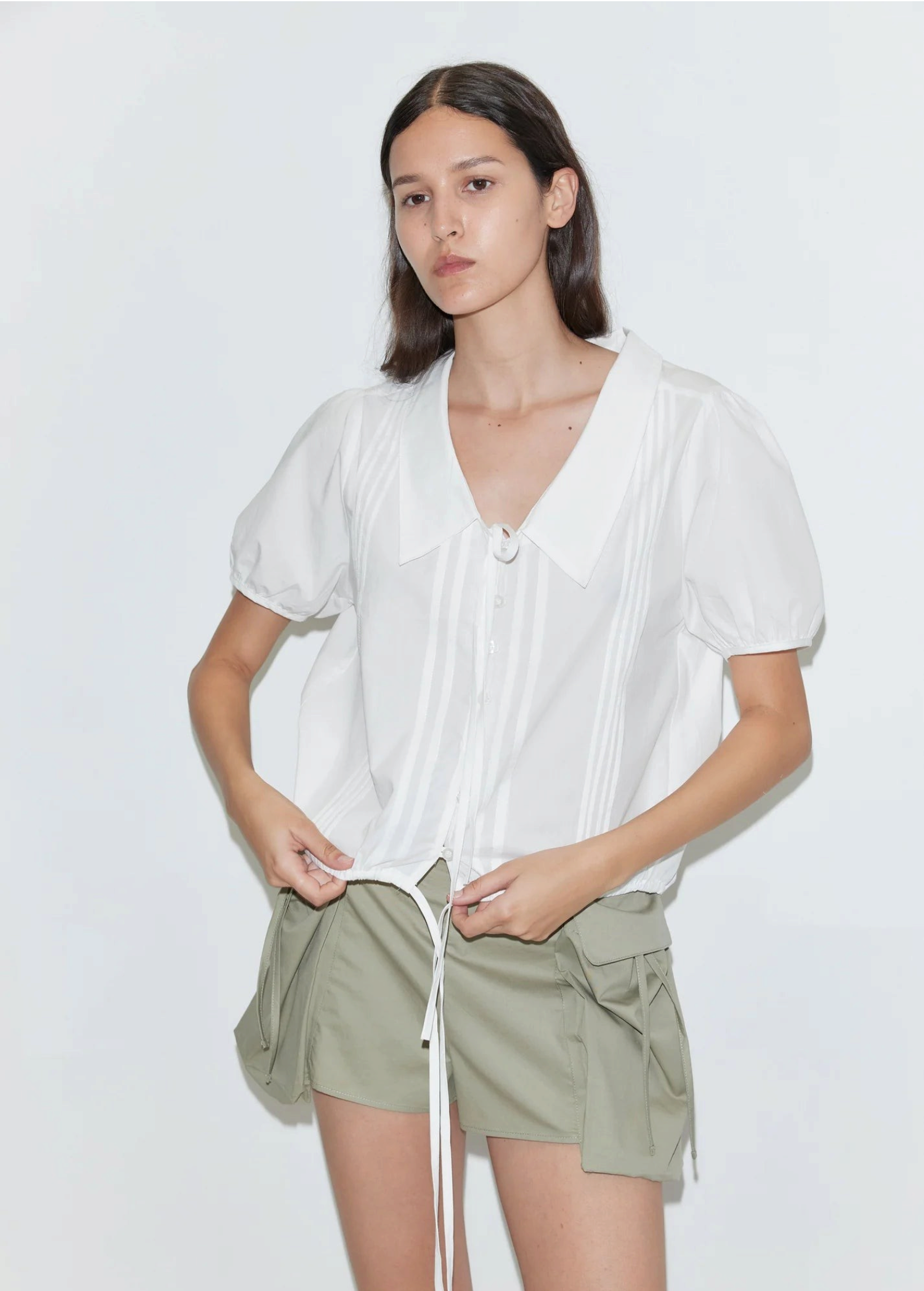 KABE SHOP INC Deiji Studios white cotton poplin top with collared V-neck, pintuck details, and adjustable drawcord hem.