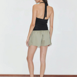 A person seen from behind wearing a fitted knit Cross Top with crisscross straps and olive green shorts.