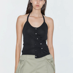 A person wears a Cross Top featuring a fitted knit halter design with an asymmetrical button-front closure and adjustable tie straps, paired with olive green shorts.