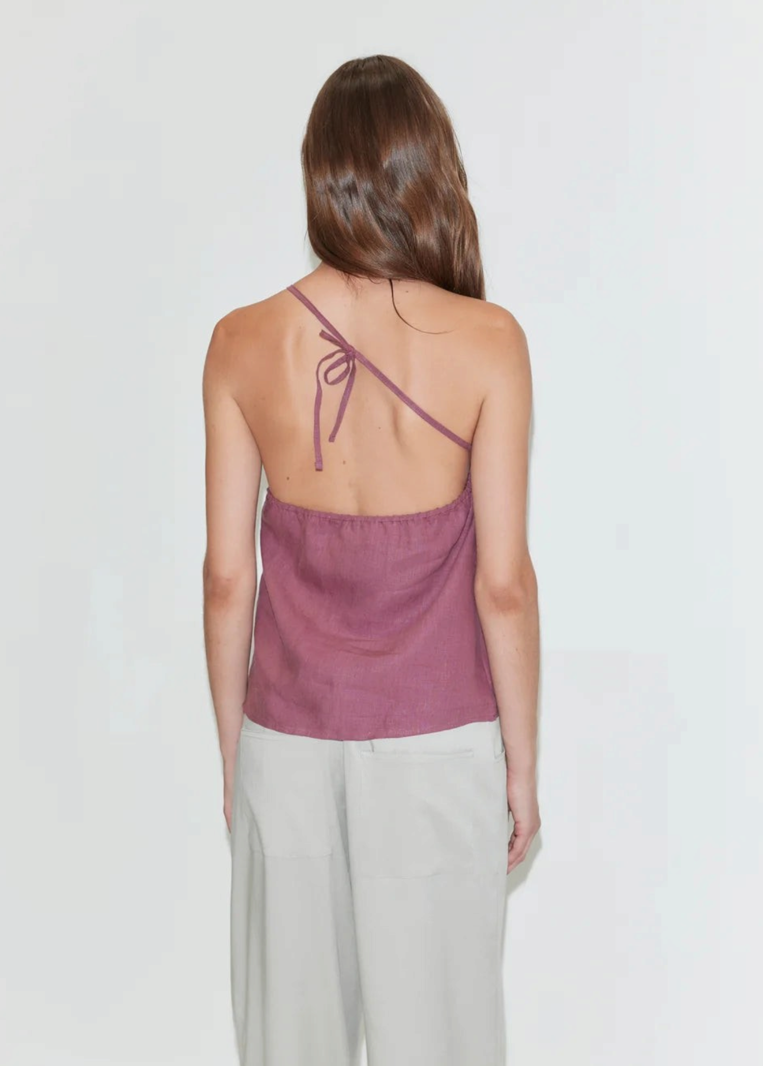 KABE SHOP INC Deiji Studios mauve linen one-shoulder top with back tie detail worn by a model from the back view