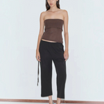 A person wearing a brown tube top, black cropped Capri Pant, and light blue kitten heels, styled for a relaxed look.