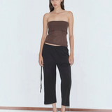 A person wearing a brown tube top, black cropped Capri Pant, and light blue kitten heels, styled for a relaxed look.