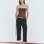 A woman wears a brown strapless top and relaxed style black Capri Pant with light blue low-heeled pumps.