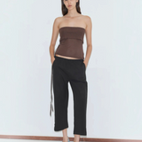 A woman wears a brown strapless top and relaxed style black Capri Pant with light blue low-heeled pumps.