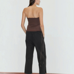 A person seen from behind, wearing a brown tube top, black Deiji Studios Capri Pant with side ties, and light blue block-heeled shoes.