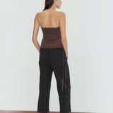 A person seen from behind, wearing a brown tube top, black Deiji Studios Capri Pant with side ties, and light blue block-heeled shoes.