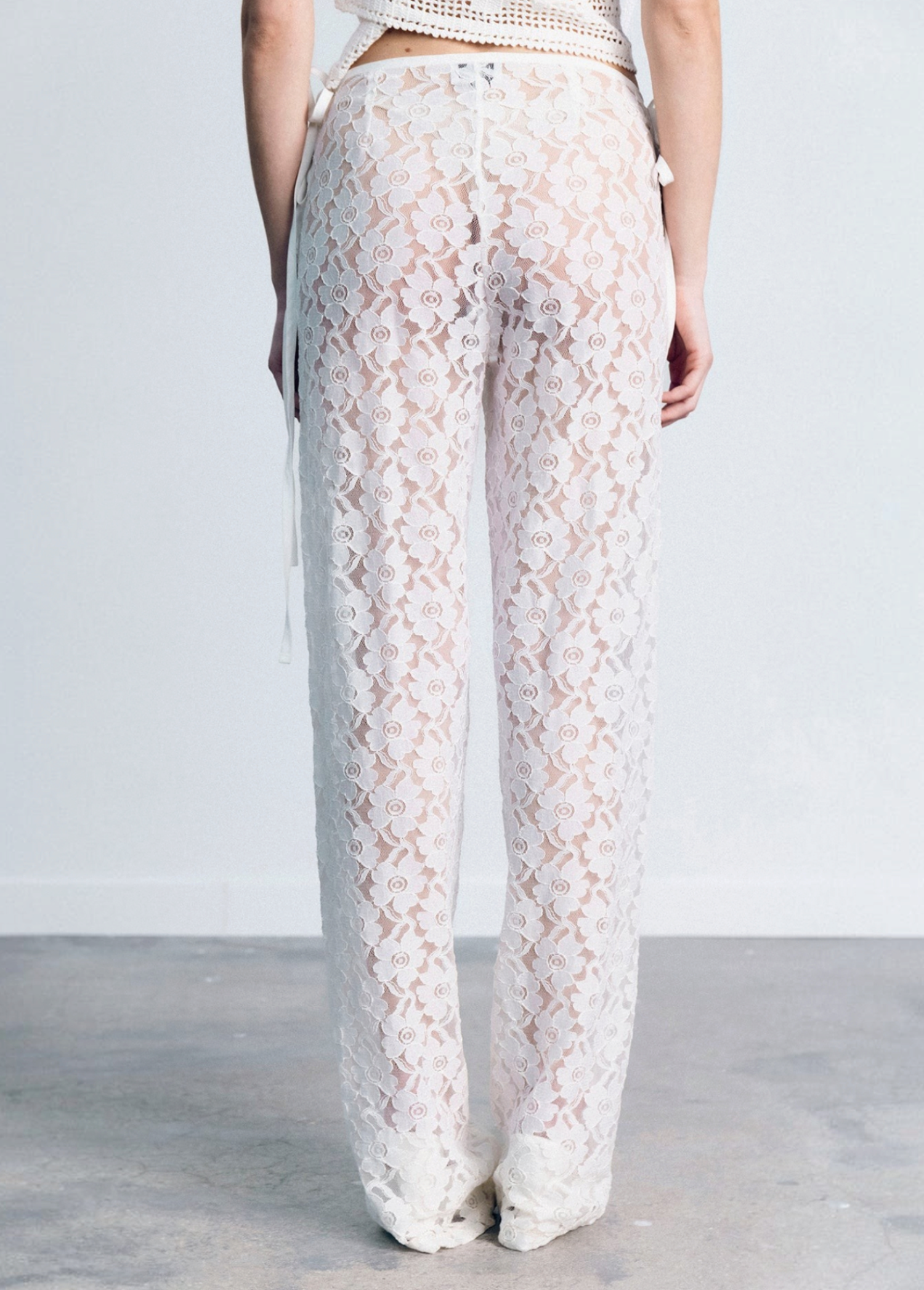 KABE SHOP INC white lace trousers with a delicate floral pattern, handkerchief waistband, and fitted silhouette.