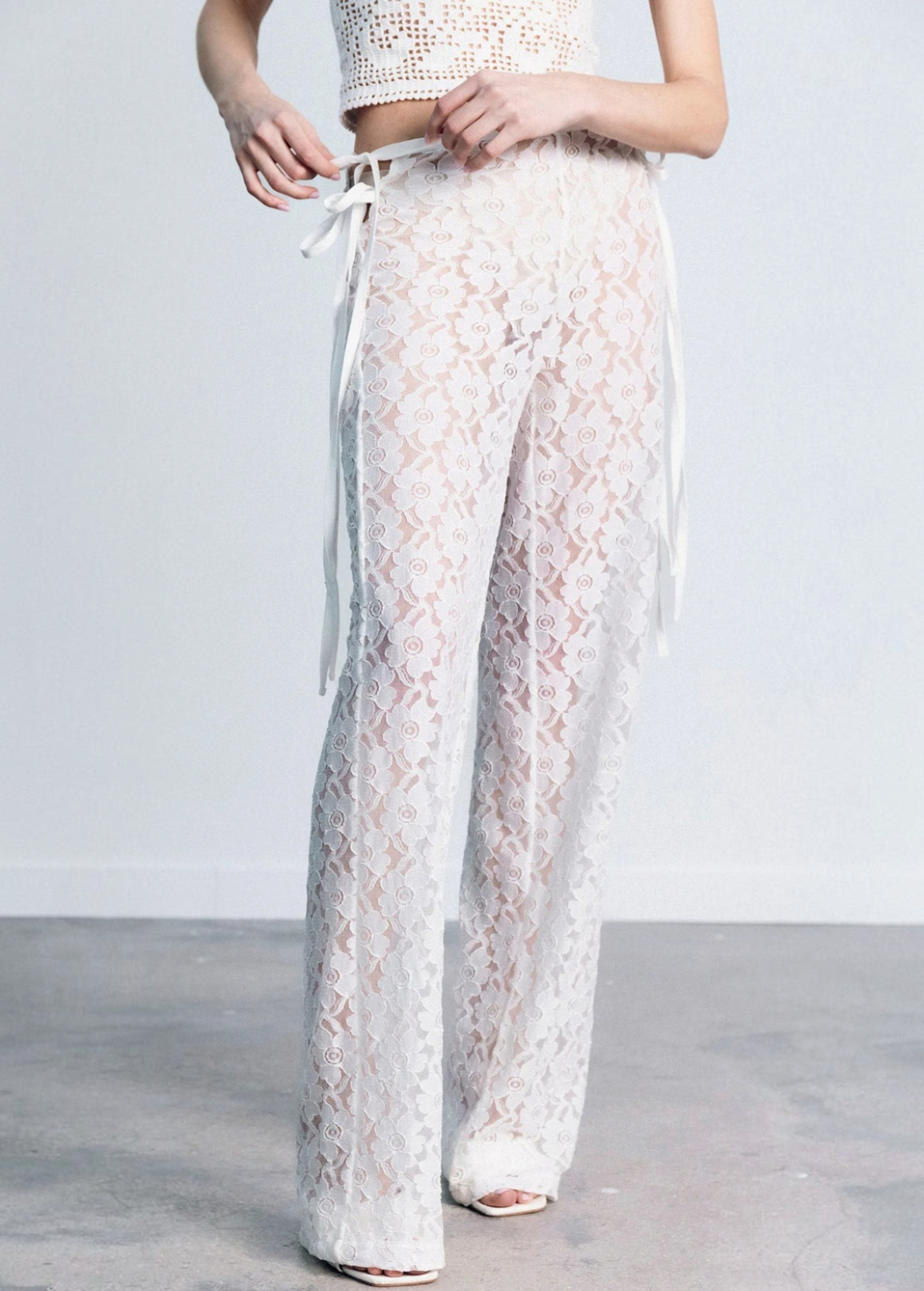 KABE SHOP INC white lace trousers with a strappy handkerchief waistband and a fitted silhouette on a model