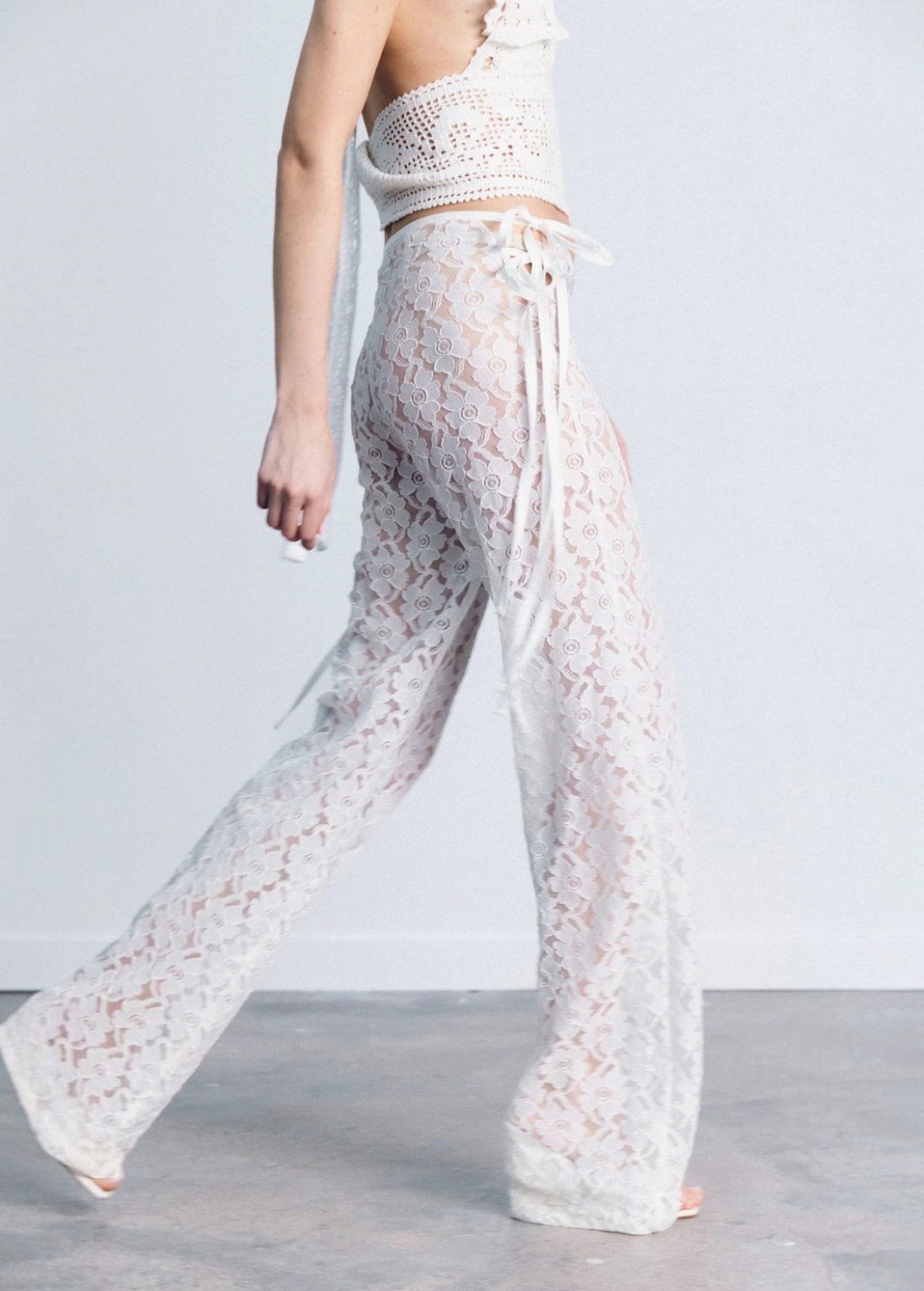 KABE SHOP INC white lace trousers with a strappy handkerchief waistband and a fitted silhouette on a model.