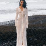 KABE SHOP INC Mirror Dress in sheer white fabric with silver embellishments on a model standing on a rocky beach