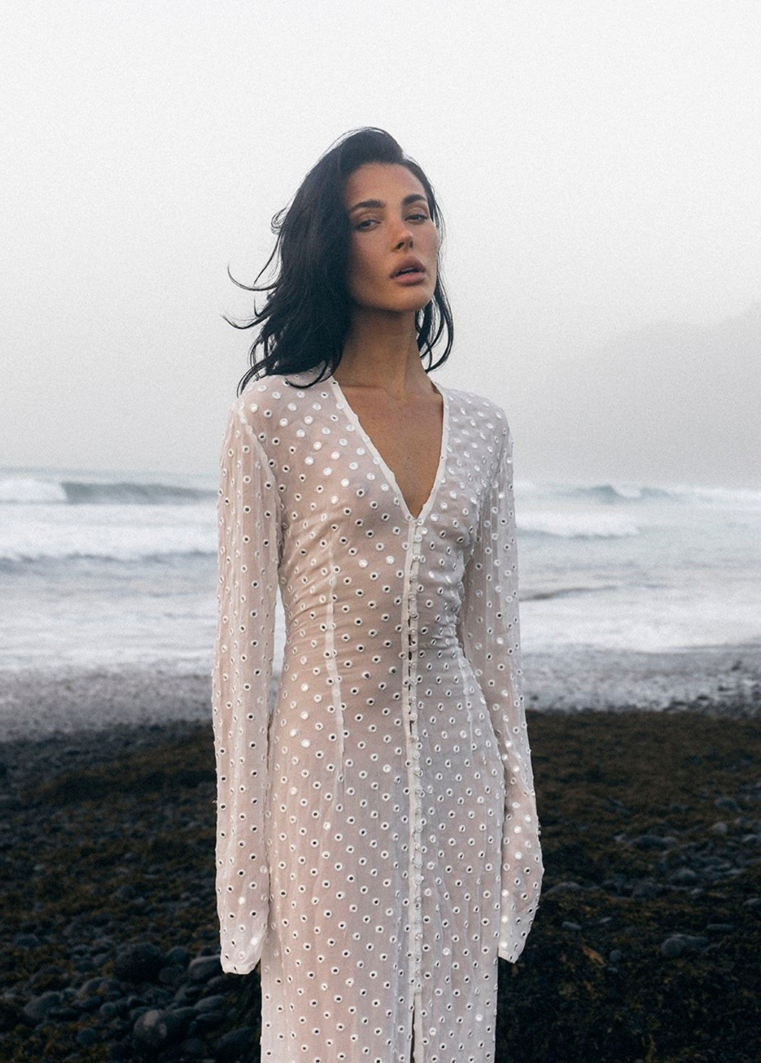 KABE SHOP INC Mirror Dress in sheer white fabric with silver embellishments worn by a model on a misty beach