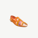 The Anzu Moccasin is an orange and tan slip-on featuring pink, yellow, and gold hand-embroidered patterns on the upper. With a flat sole and rounded toe, this sustainable shoe is inspired by the classic moccasin and is displayed on a white background.