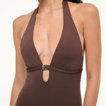 A brown La Jolla Swimwear one-piece swimsuit with a deep halter neckline and a silver crescent-shaped hardware accent at the center.