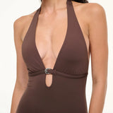 A brown La Jolla Swimwear one-piece swimsuit with a deep halter neckline and a silver crescent-shaped hardware accent at the center.