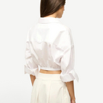 Back view of a person wearing the white Lisa Top, featuring a collared neckline, three-quarter length cuffed sleeves, and a wide elastic hem, styled for everyday dressing.