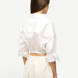 Back view of a person wearing the white Lisa Top, featuring a collared neckline, three-quarter length cuffed sleeves, and a wide elastic hem, styled for everyday dressing.