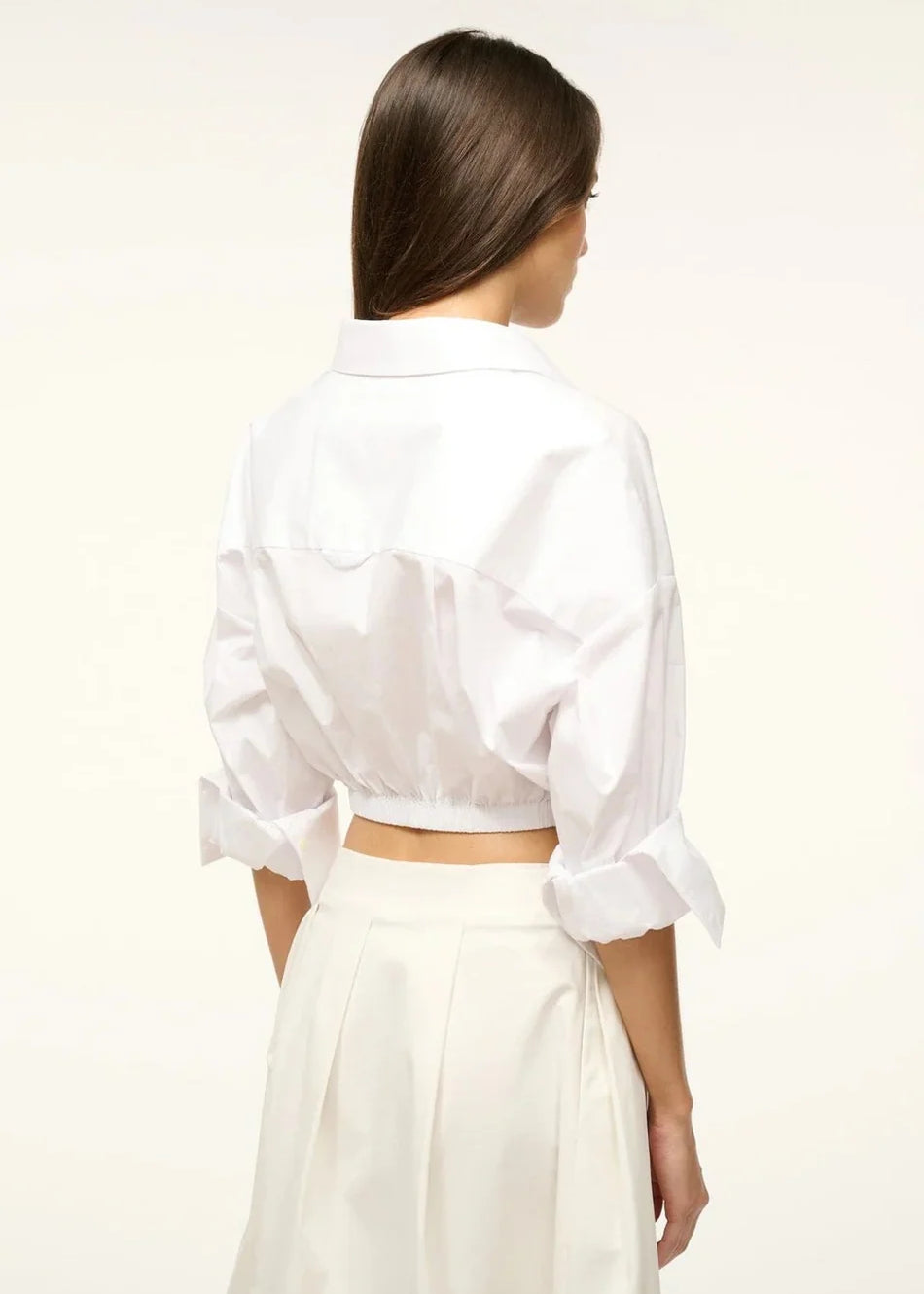 Back view of a person wearing the white Lisa Top, featuring a collared neckline, three-quarter length cuffed sleeves, and a wide elastic hem, styled for everyday dressing.