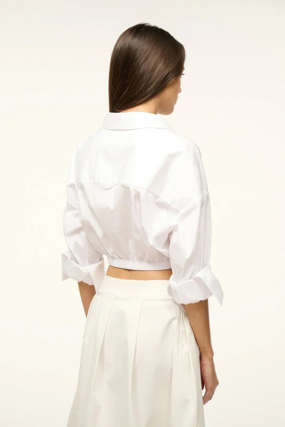 Back view of a person wearing the white Lisa Top, featuring a collared neckline, three-quarter length cuffed sleeves, and a wide elastic hem, styled for everyday dressing.
