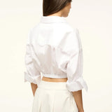 Back view of a person wearing the white Lisa Top, featuring a collared neckline, three-quarter length cuffed sleeves, and a wide elastic hem, styled for everyday dressing.