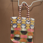 KABE SHOP INC Kanpur bag featuring a vibrant geometric mesh pattern in multi-colored circles and striped handles.