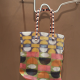 KABE SHOP INC Kanpur bag featuring a vibrant geometric mesh pattern in multi-colored circles and striped handles.