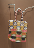KABE SHOP INC Kanpur bag featuring a vibrant geometric mesh pattern in multi-colored circles and striped handles.