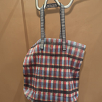 KABE SHOP INC Kanpur bag featuring a vibrant multi-colored plaid mesh pattern with black and white striped handles.
