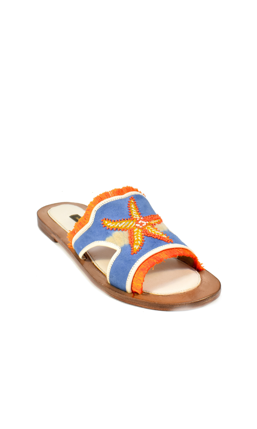 The Mazu Slide is a flat sandal featuring a blue upper with orange trim and a beaded starfish embellishment on top. Inspired by Silk Route artisan footwear, this open-toe sandal is finished with a tan sole, making it perfect for effortless summer style.