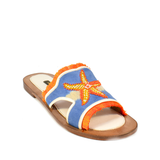 The Mazu Slide is a flat sandal featuring a blue upper with orange trim and a beaded starfish embellishment on top. Inspired by Silk Route artisan footwear, this open-toe sandal is finished with a tan sole, making it perfect for effortless summer style.