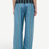 Back view of the Mateo Pant, featuring wide-leg trousers in blue and teal vertical stripes with a black elastic waistband.