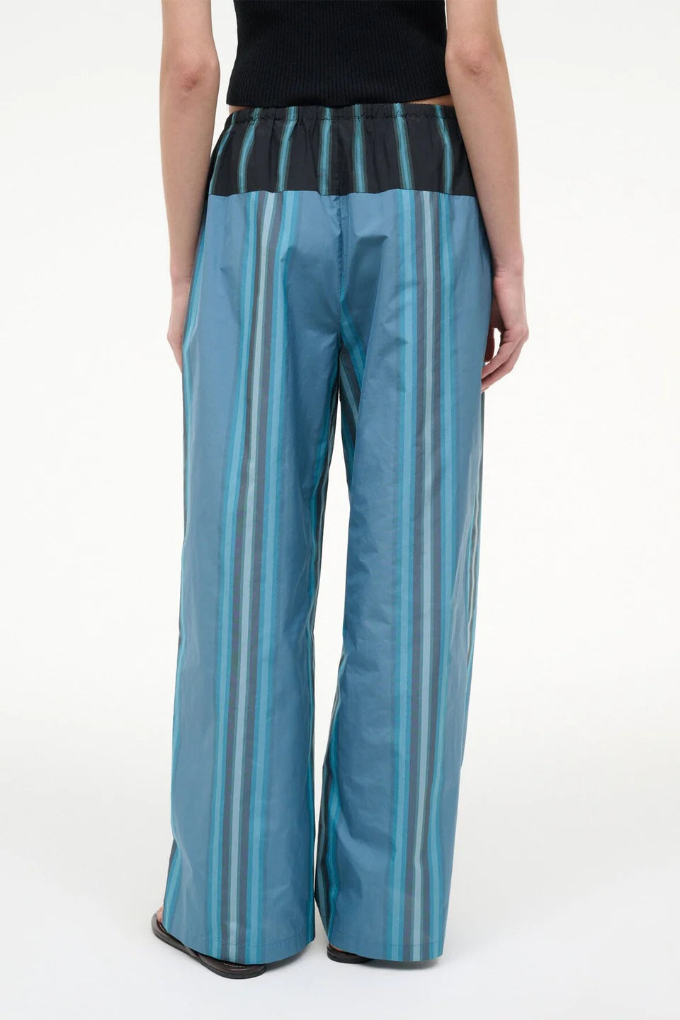 Back view of the Mateo Pant, featuring wide-leg trousers in blue and teal vertical stripes with a black elastic waistband.