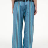 Back view of the Mateo Pant, featuring wide-leg trousers in blue and teal vertical stripes with a black elastic waistband.