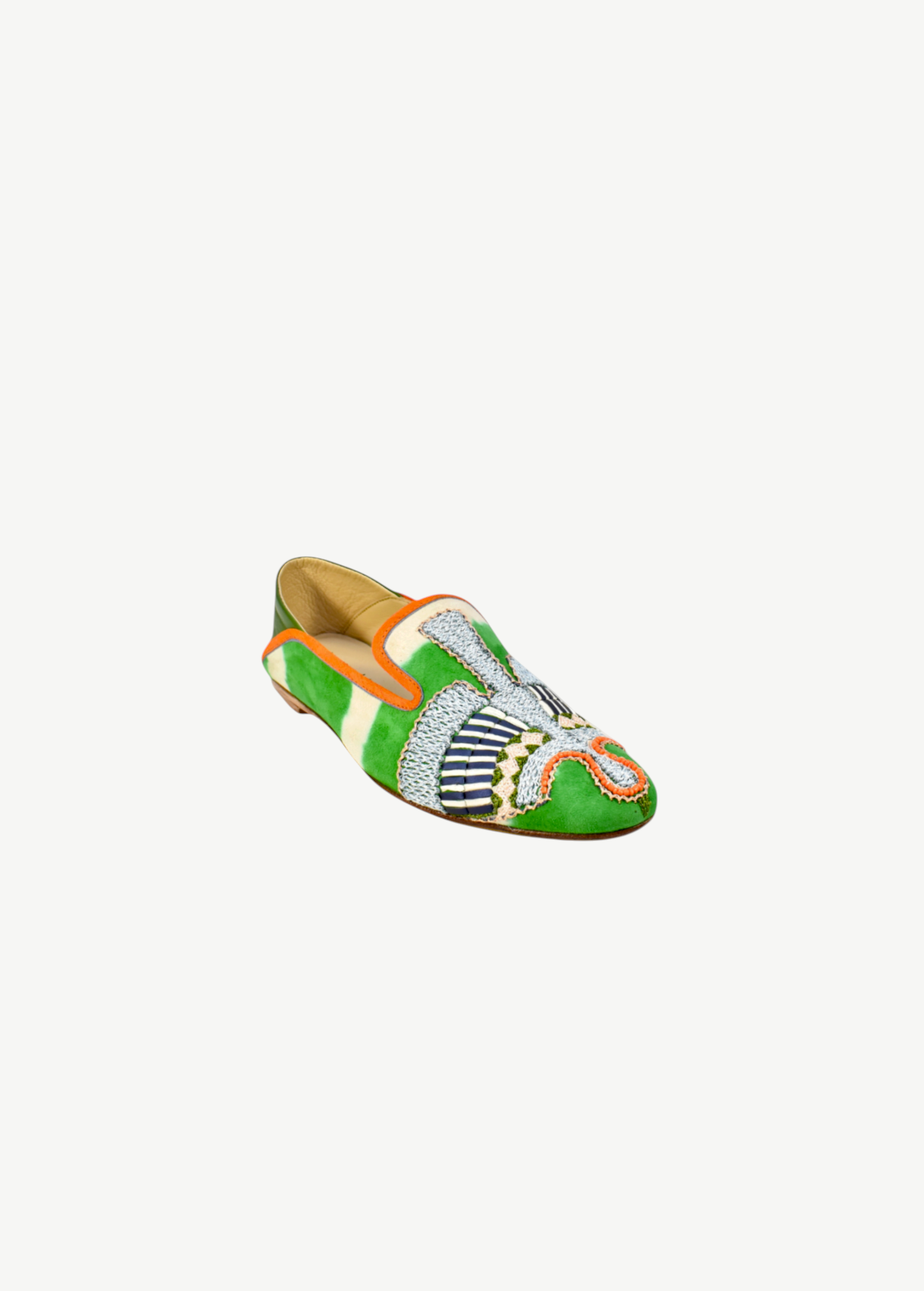 The Anzu Moccasin is a vibrant babouche-style loafer crafted from green, orange, and white suede, adorned with intricate beaded details and hand-embroidered moccasin patterns on the front and sides.