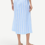 Back view of a person wearing a light blue and white striped Shore Skirt with an elastic waistband and brown flip-flops, an example of effortless styling.