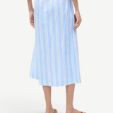 Back view of a person wearing a light blue and white striped Shore Skirt with an elastic waistband and brown flip-flops, an example of effortless styling.