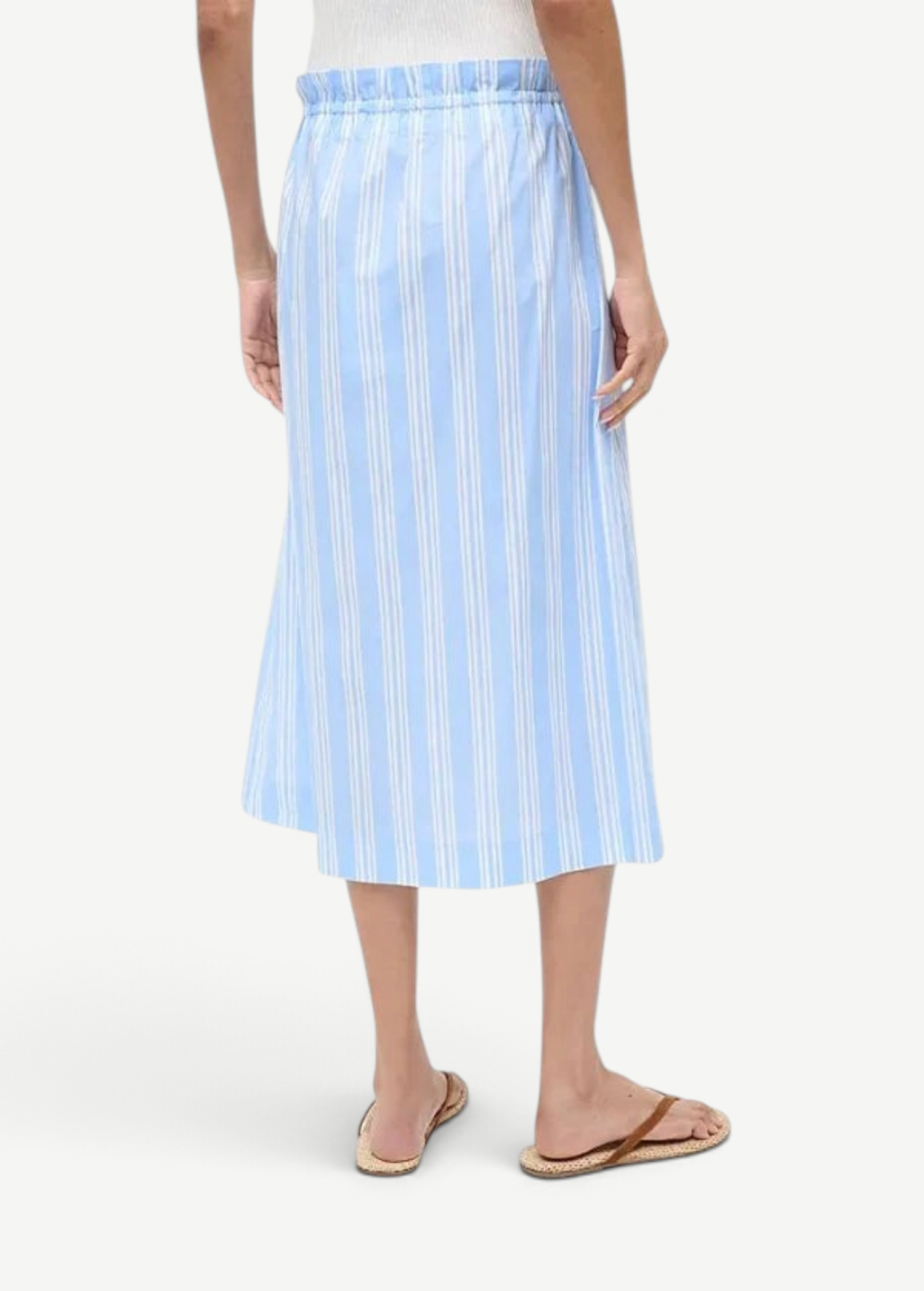 Back view of a person wearing a light blue and white striped Shore Skirt with an elastic waistband and brown flip-flops, an example of effortless styling.