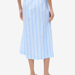 Back view of a person wearing a light blue and white striped Shore Skirt with an elastic waistband and brown flip-flops, an example of effortless styling.