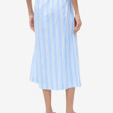 Back view of a person wearing a light blue and white striped Shore Skirt with an elastic waistband and brown flip-flops, an example of effortless styling.