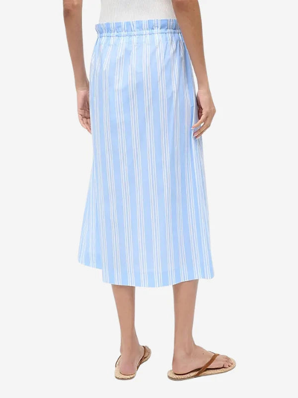Back view of a person wearing a light blue and white striped Shore Skirt with an elastic waistband and brown flip-flops, an example of effortless styling.