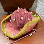 KABE SHOP INC crochet tie-dye hat in pink and green with decorative seashells on a wooden chair